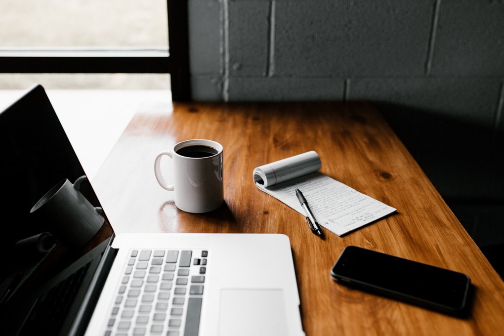 contact a plumber using your laptop on desk with coffee pen paper