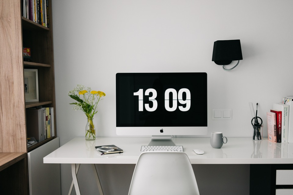 mac screen with time white table white wall black lamp wood bookshelf