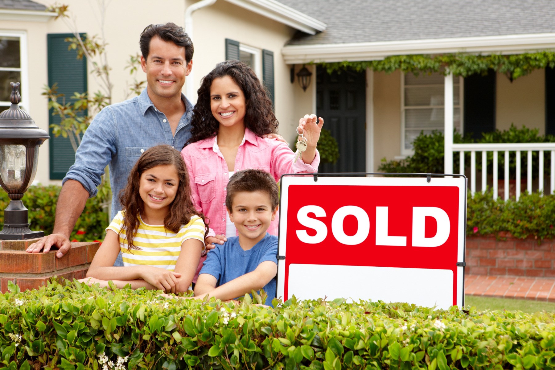 selling a home family in front of a house with sold sign