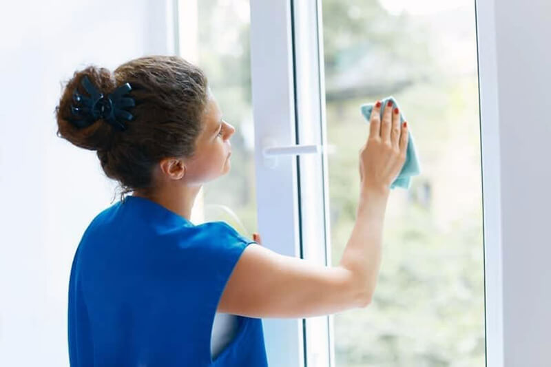 Cleaning Services woman in blue cleaning window treatment