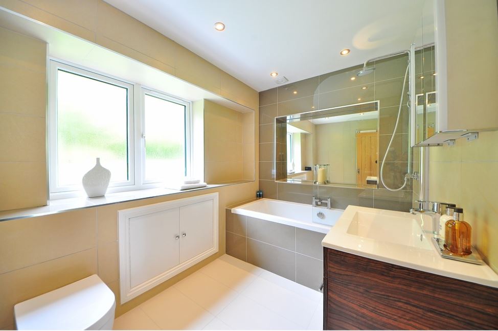 bathroom with white bath, yellow walls, mirror, vanity, rain shower and downlights